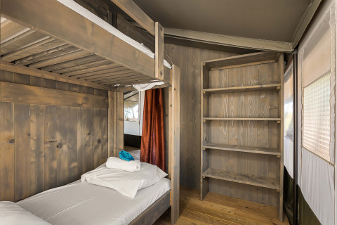 Indvendig visning af Safari Tent Luxury med køjeseng og træhylder på Camping Lanterna i Kroatien.