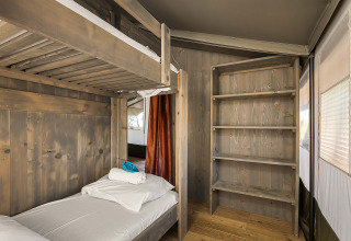 Vista interior de Safari Tent Luxury con litera y estanterías de madera en Camping Lanterna, Croacia.