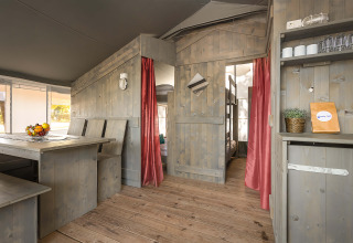 Interior of Safari Tent Luxury at Camping Lanterna, Croatia, featuring wooden furniture and red curtains.