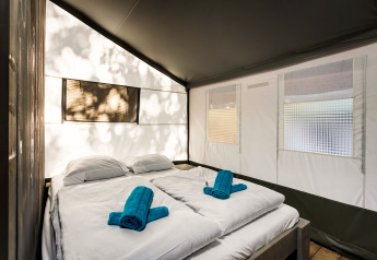 Binnenkant van de Safari Tent Luxury op Camping Lanterna in Kroatië met tweepersoonsbed en handdoeken.