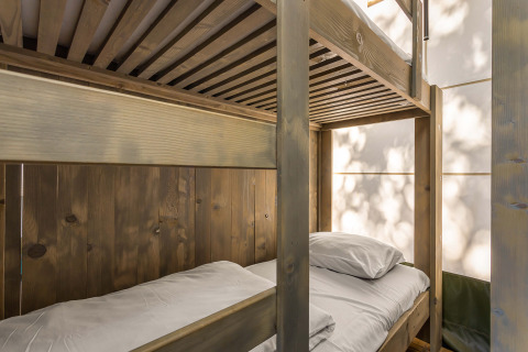 Literas de madera en Safari Tent Luxury de Camping Lanterna, Croacia, iluminadas por luz natural.