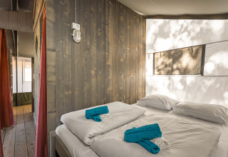 Interno di una tenda safari luxury al Camping Lanterna in Croazia con letto matrimoniale e asciugamani puliti.