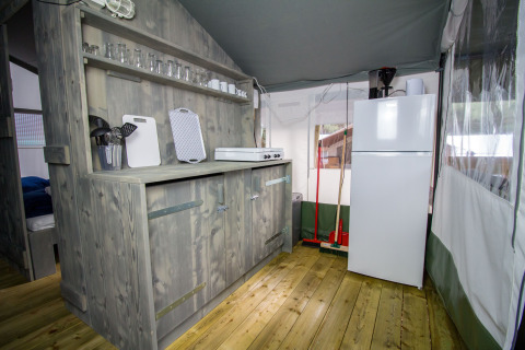 Zona de cocina en una tienda safari de lujo en Camping Lanterna, Croacia, con armarios de madera.