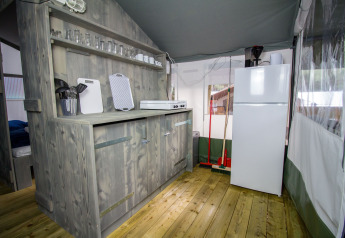 Area cucina in una tenda safari di lusso al Camping Lanterna, Croazia, con mobili in legno.