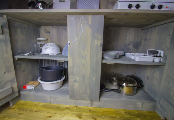 Küchenschrank mit Geschirr, Töpfen und Küchenutensilien in einem Safari-Luxuszelt auf Camping Lanterna, Kroatien.