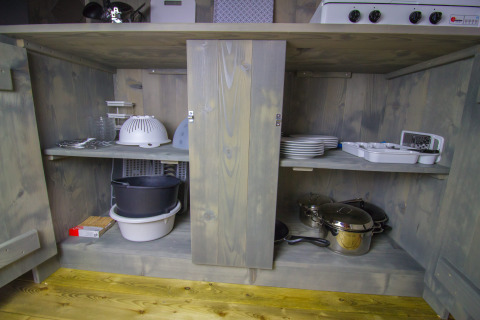 Küchenschrank mit Geschirr, Töpfen und Küchenutensilien in einem Safari-Luxuszelt auf Camping Lanterna, Kroatien.
