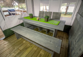 Eettafel in Safari Tent Luxury op Camping Lanterna, Kroatië, met houten bank en groene tafelloper.