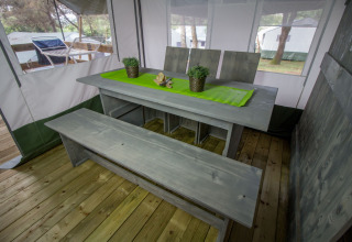 Set da pranzo nel Safari Tent Luxury al Camping Lanterna, Croazia, con panca di legno e tovaglia verde.