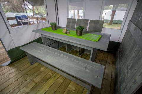 Mesa de comedor en Safari Tent Luxury en Camping Lanterna, Croacia, con banco de madera y mantel verde.