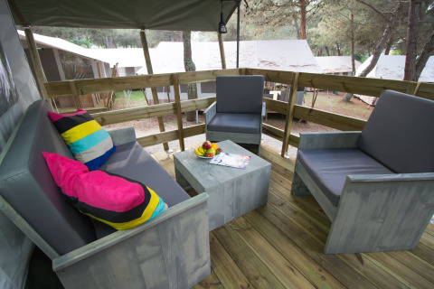 Zona de estar al aire libre con sillones grises y cojines coloridos en Safari Tent Luxury, Camping Lanterna.
