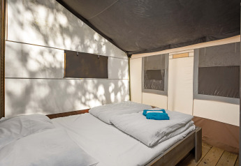 Vista interna di una tenda safari di lusso con letto matrimoniale al Camping Lanterna in Croazia.