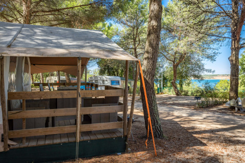 Safari Tent Luxury al Camping Lanterna in Croazia tra pini, con vista sul mare sullo sfondo.