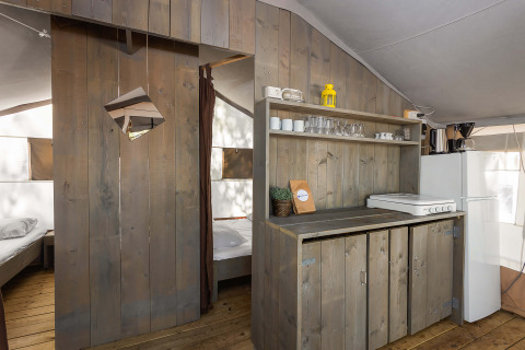 Entrada al dormitorio y zona de cocina dentro de una tienda safari de lujo en Camping Lanterna, Croacia.