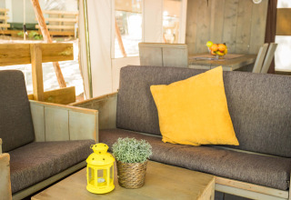 Interior de una tienda safari de lujo en Camping Lanterna, Croacia, con cojín y linterna amarillos.
