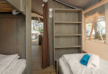 Indvendig udsigt af Safari Tent Luxury på Camping Lanterna i Kroatien med senge, hylder og trægulv.