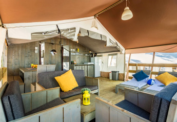Interieur van een luxe safaritent op Camping Lanterna in Kroatië met houten meubels en kleurrijke kussens.