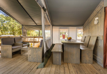 Innenbereich des Safari Tent Luxury auf Camping Lanterna, Kroatien, mit Holzmöbeln und Überdachung.