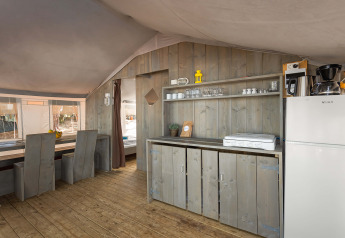 Interior of Safari Tent Luxury at Camping Lanterna in Croatia with kitchenette, fridge and rustic furniture.