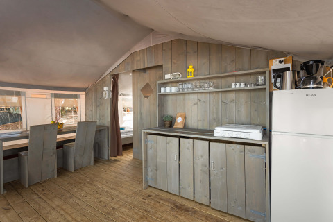 Interior of Safari Tent Luxury at Camping Lanterna in Croatia with kitchenette, fridge and rustic furniture.
