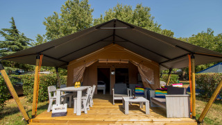 Tienda Safari Comfort con aire acondicionado, terraza de madera, asientos y mesa al aire libre, ambiente natural.