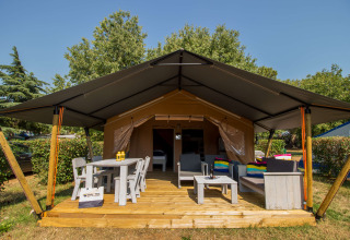 Tenda Safari Comfort con aria condizionata, veranda in legno, sedie, tavolo e divani all’aperto nel verde.
