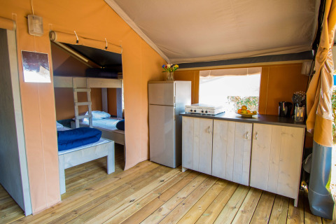 Intérieur de la tente Safari Comfort avec cuisine, réfrigérateur et lits superposés au Camping Porto Sole, Croatie.