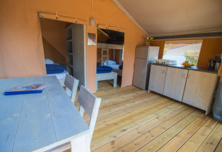 Interior de la tienda Safari Comfort con aire acondicionado, cocina y comedor en Camping Porto Sole, Croacia.