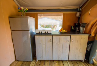 Keukengedeelte in een safaritent met koelkast, kookplaat en kasten op Camping Porto Sole, Kroatië.