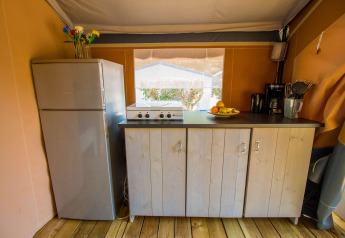 Køkkenområde i en safaritelte med køleskab, komfur og skabe på Camping Porto Sole, Kroatien.