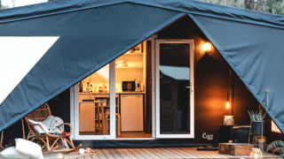 Knusse ingang van het Cottage Midi Suite safaritent met sfeervolle verlichting en modern interieur.