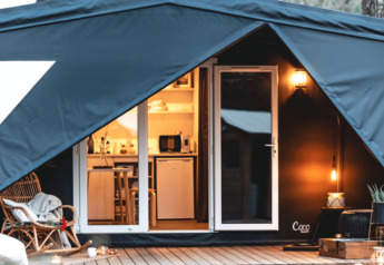 Knusse ingang van het Cottage Midi Suite safaritent met sfeervolle verlichting en modern interieur.