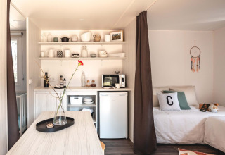 Interieur van Cottage Midi Suite safaritent bij Papillon Country Resort met keuken en bed.