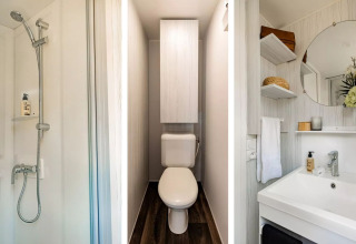 Baño moderno en una tienda tipo cabaña safari con ducha, inodoro y lavabo en Papillon Country Resort.