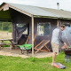 Mand griller foran safari-telt ved Feather Down Heydon Grove Farm, England, picnicbord i baggrunden.