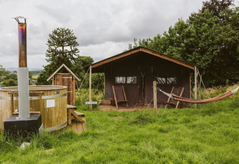 Safari tent with private hot shower, hot tub, and hammock at Feather Down Hollings Hill, United Kingdom.