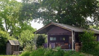 Safari tent with private hot shower and hot tub surrounded by greenery at Feather Down Manor Farm, UK.