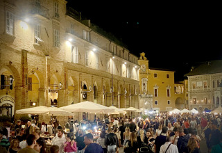 Natte marked, travle mennesker og oplyste bygninger i Agriturismo Angeli Sognanti, Marche, Italien.