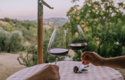 To personer skåler med vinglas ved et bord med ternet dug på Agriturismo Angeli Sognanti, Marche, Italien.