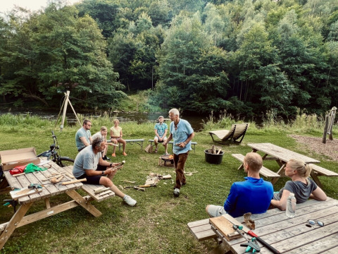 Gruppo di persone sedute e in piedi intorno a tavoli da picnic al Camp Kyllburg, Renania-Palatinato, Germania.