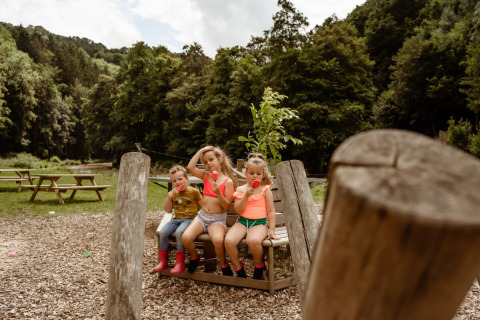 Tre bambini mangiano il gelato su una panchina al Camp Kyllburg, parco vacanze nella Renania-Palatinato, Germania.