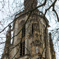 Torre de iglesia histórica en Kyllburg, Alemania, vista tras ramas desnudas en un día gris.