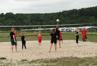 Børn og voksne spiller volleyball på stranden ved Rosenvold Strand Camping i det centrale Danmark.