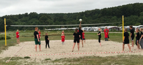 Kinderen en volwassenen spelen volleybal op het strand bij Rosenvold Strand Camping, Centraal-Denemarken.