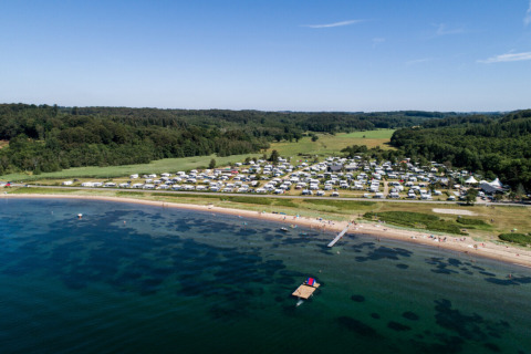 Vista aérea de Rosenvold Strand Camping con caravanas junto a la playa y bosque en la región central de Dinamarca.