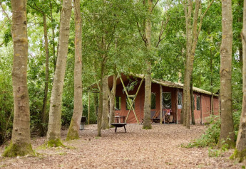 Tenda safari al Feather Down Layer Marney Tower, UK, tra gli alberi con doccia privata e vasca idromassaggio.