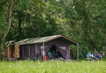Tenda safari con doccia privata accanto alla tenda a Feather Down Moor Farm, Regno Unito, con famiglia fuori.