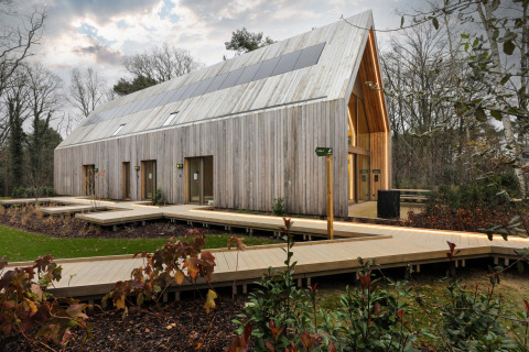 Moderne hytte i træ med solpaneler på taget hos Woodz Lodges feriepark i Limburg, Belgien, omgivet af natur.