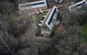 Luftfoto af moderne hytter med store glasfacader i skovrige omgivelser ved Woodz Lodges i Belgisk Limburg.