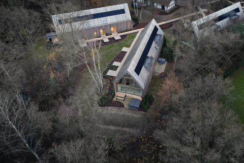 Aerial view of modern lodges with glass fronts nestled among trees at Woodz Lodges in Belgian Limburg.