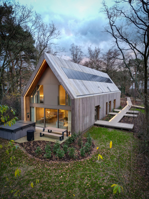 Moderne houten lodge met grote ramen en zonnepanelen in Woodz Lodges vakantiepark, Limburg, België.
